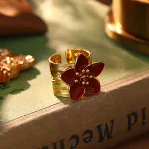 Detailansicht eines Vintage-Goldrings mit dunkelrotem Blumendesign auf einem Buch