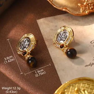 Detailed macro view of vintage coin drop earrings with gold ornate border and dark bead