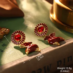 Makroansicht von Vintage-Ohrringen im Hofstil mit roten Blumen und Vögeln