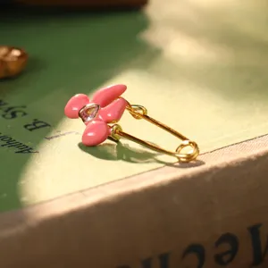 Detailansicht eines rosa emaillierten Blumen-Ansteckohrings mit herzförmigem Edelstein