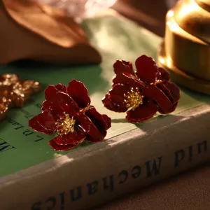 Detaillierte Makroansicht von roten Vintage-Blumenohrringen auf einem alten Buch.