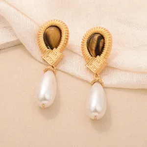 Détail de boucles d'oreilles vintage en or avec pierres oeil de tigre et perles