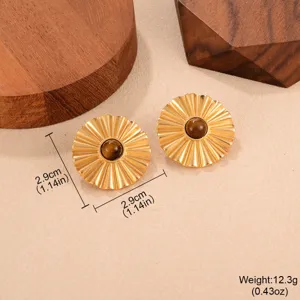 Détail de boucles d'oreilles vintage plissées dorées avec pierre d'œil-de-tigre.