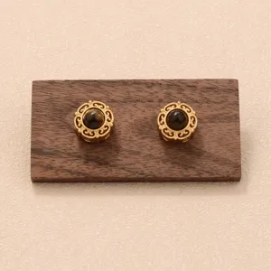 Vue détaillée de boucles d'oreilles vintage en filigrane d'or avec pierre œil de tigre.