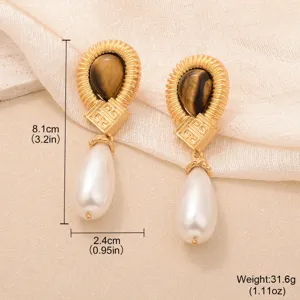 Vue détaillée de boucles d'oreilles rétro en or avec œil de tigre et perles en poire