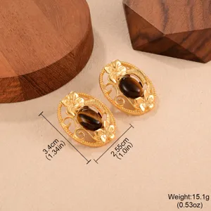 Gros plan détaillé de boucles d'oreilles vintage dorées avec pierre œil de tigre et fleurs