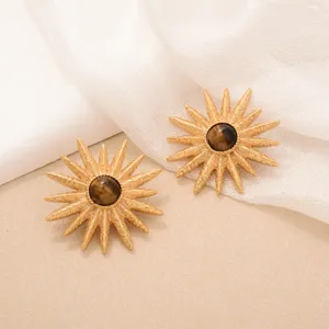 Detailed macro view of vintage sunburst earrings with central brown tiger eye stones.