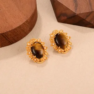Détail des boucles d'oreilles oeil de tigre vintage avec monture florale et perles.