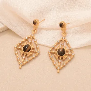 Vue détaillée de boucles d'oreilles vintage en or avec pierres œil de tigre et strass