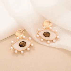 Vintage gold tiger eye stud earrings with white pearl accents and evil eye design