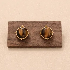 Gros plan de boucles d'oreilles œil de tigre vintage avec monture dorée sur bois