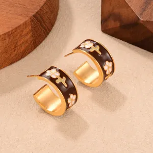 Close-up view of vintage C-shaped Maillard brown earrings featuring white flower details