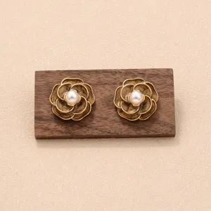 Vue détaillée de boucles d'oreilles fleurs marron vintage avec perles sur support bois
