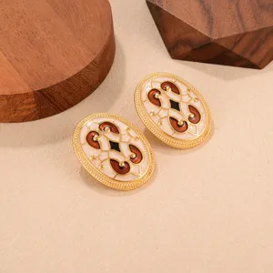 Détail de boucles d'oreilles rétro en émail avec motif marron et crème doré