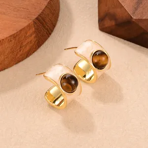 Detailed macro view of vintage C-shape earrings with tiger eye stone and gold finish