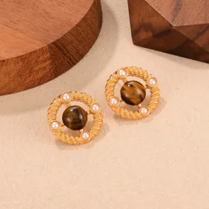 Primer plano de pendientes vintage de ojo de tigre con perlas en marco de cuerda dorado
