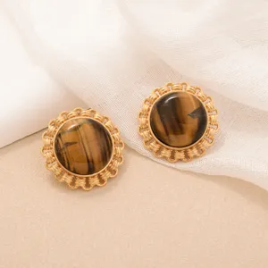 Detailed macro shot of vintage gold sunflower earrings with tiger's eye cabochon stone.