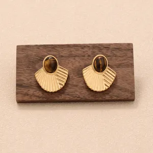 Vue détaillée de boucles d'oreilles coquillages en or avec pierres œil de tigre.