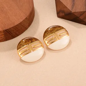 Détail des boucles d'oreilles rétro Maillard avec motif géométrique doré et résine brune.