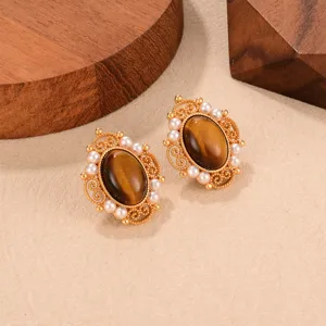 Close-up of vintage French earrings with tiger eye stone and pearls on wood blocks