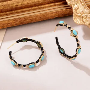 Detail of vintage C-shaped hoop earrings with black enamel and turquoise accents.