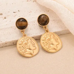 Gros plan détaillé de boucles d'oreilles vintage en or avec pierres œil de tigre et pièces.