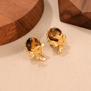 Close-up of vintage gold earrings featuring brown tiger eye stones and ribbon design.