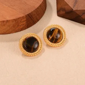 Close-up detail showing the texture of vintage tiger's eye stud earrings with gold braided frames.