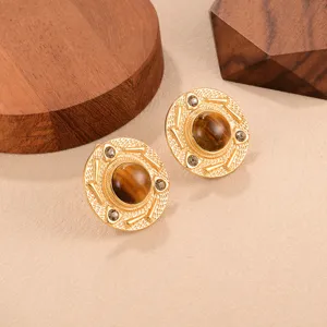 Gros plan de boucles d'oreilles vintage dorées avec une pierre oeil de tigre centrale