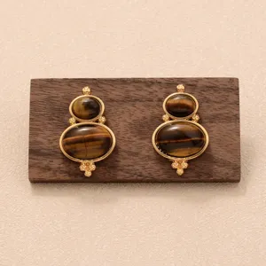 Vue détaillée de boucles d'oreilles œil de tigre vintage avec montures dorées.
