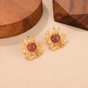 Vista detallada de pendientes vintage dorados con un centro de piedra marrón brillante