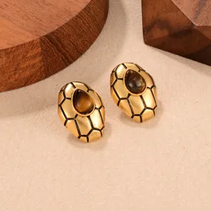 Vista detallada de pendientes vintage dorados con piedra ojo de tigre y grabado