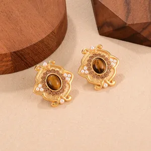 Détail macro de boucles d'oreilles vintage en or avec pierre œil de tigre et petites perles