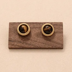 Détail de boucles d'oreilles vintage avec pierre œil de tigre et bordure dorée