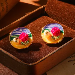 Détail macro de boucles d'oreilles émail vintage avec fleur rose et perle naturelle
