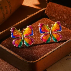 Gros plan de boucles d'oreilles papillon en émail coloré dans un coffret vintage