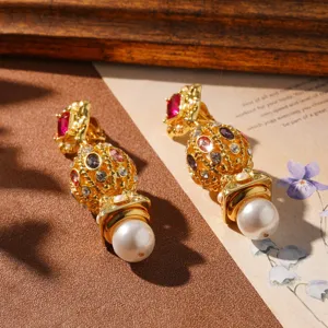 Close-up of vintage gold-tone earrings with multi-color stones and white pearls.