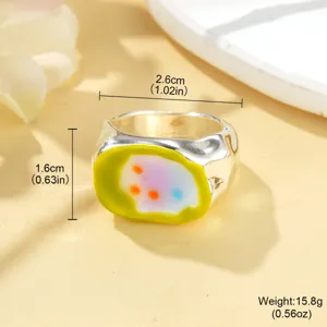Gros plan d'une bague argentée texturée avec une incrustation en émail coloré.