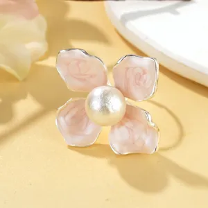 Détail en gros plan d'une bague ouverte en argent avec fleur en émail et perle