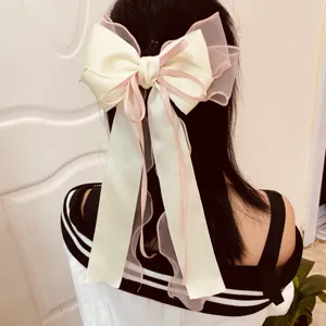 Back view of a large cream and pink layered ribbon bow hair clip on black hair.
