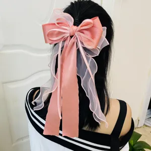 Detail view of a large pink fairy-style ribbon bow hair clip worn on the back of the head.