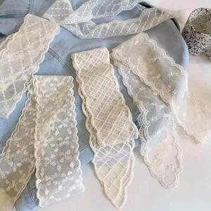 Macro detail of various vintage lace hair ribbons with floral embroidery on light denim