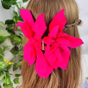 Detailed back view of a large hot pink fabric bow hair claw clip styled on braided hair