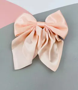 Λεπτομερής άποψη μεγάλου κλιπ μαλλιών με σατέν φιόγκο σε ροδακινί χρώμα και λάμψη