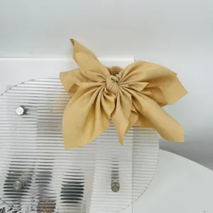 Close-up of a large mustard yellow fabric bow hair claw clip with linen texture.