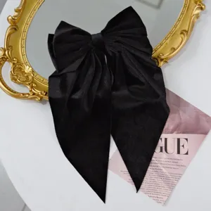 Macro view of black velvet hair clip showing large bow design with elegant long streamers