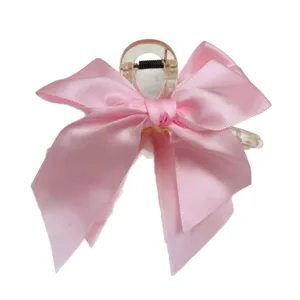 Elegant pink satin bow hair claw clip featuring a large transparent shark grip design