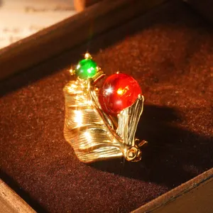 Vue détaillée d'une broche caniche dorée avec perles rouges et vertes de style rétro