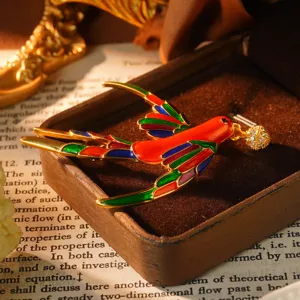 Vue détaillée d'une broche hirondelle en émail coloré dans une boîte à bijoux marron luxe