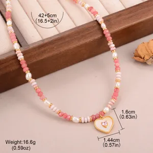Detailopname van de hartvormige ketting met roze en witte kralen en gouden accenten